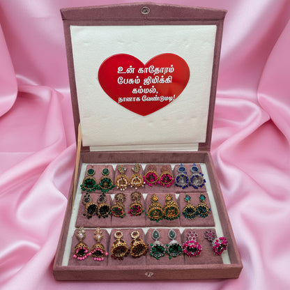 Box of earrings with a heart-shaped card on a pink background